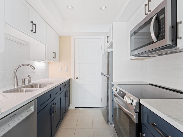 6300 Midnight Pass Rd Unit 5, Sarasota, FL 34242 - kitchen with stainless steel appliances, a sink, tasteful backsplash, white cabinetry, and light tile patterned flooring