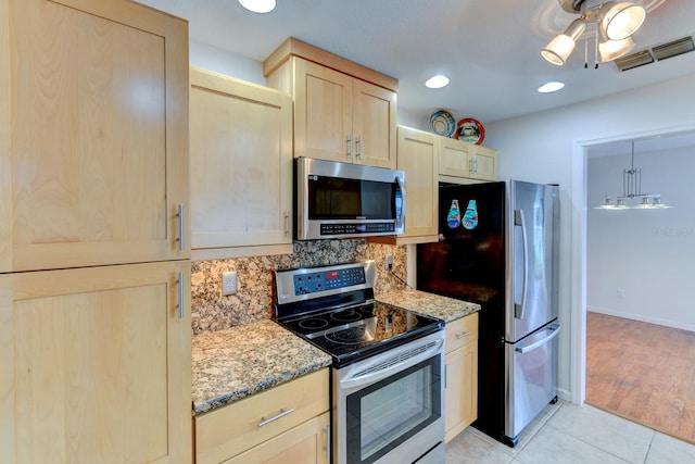 8402 13th Ave NW, Bradenton, FL 34209 - kitchen with stainless steel appliances, light brown cabinetry, light stone counters, light tile patterned floors, and backsplash