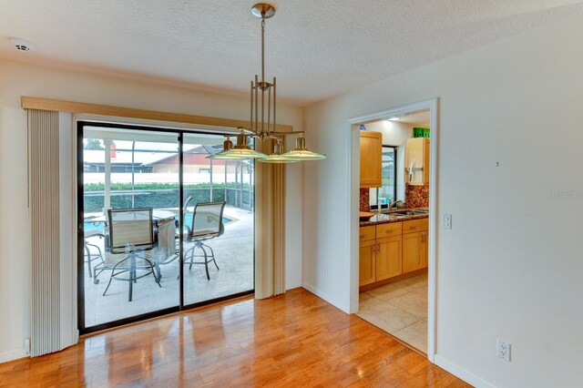 8402 13th Ave NW, Bradenton, FL 34209 - dining room with light wood finished floors, a textured ceiling, and baseboards