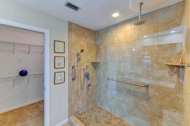 8402 13th Ave NW, Bradenton, FL 34209 - bathroom with tiled shower, a spacious closet, tile patterned floors, and baseboards