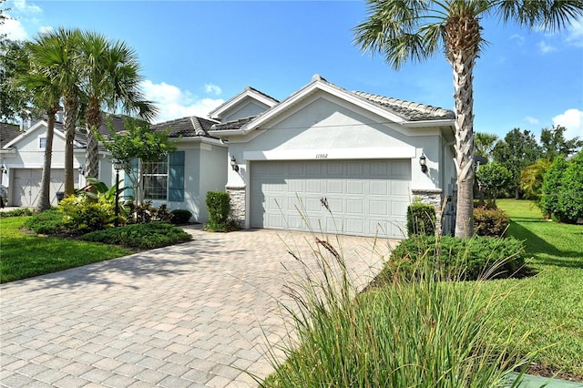 11502 Golden Bay Pl, Bradenton, FL 34211 - ranch-style home with stucco siding, a garage, decorative driveway, a front yard, and a tile roof