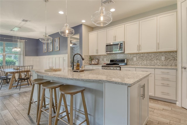 11502 Golden Bay Pl, Bradenton, FL 34211 - kitchen featuring stainless steel microwave, range, a sink, light wood-type flooring, and wainscoting