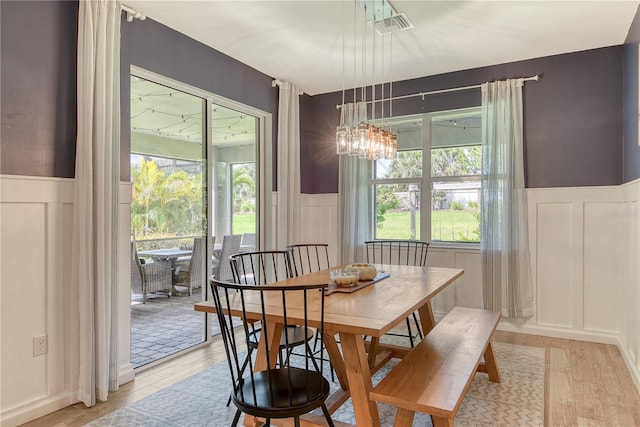 11502 Golden Bay Pl, Bradenton, FL 34211 - dining room featuring a decorative wall, a wainscoted wall, healthy amount of natural light, a chandelier, and light wood-style flooring