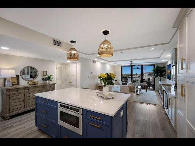 2045 Gulf Of Mexico Dr Unit M1-505, Longboat Key, FL 34228 - kitchen with blue cabinets, stainless steel microwave, light countertops, light wood finished floors, and open floor plan