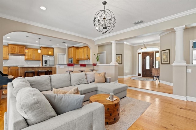 5373 Anthony Ln, Sarasota, FL 34233 - living room with light wood finished floors, baseboards, ornamental molding, arched walkways, and a chandelier