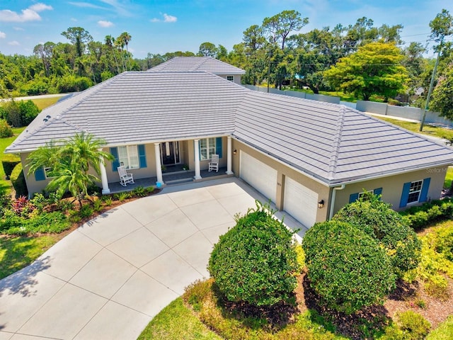 5373 Anthony Ln, Sarasota, FL 34233 - ranch-style house featuring a porch, concrete driveway, a garage, stucco siding, and a tiled roof