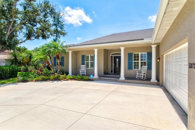 5373 Anthony Ln, Sarasota, FL 34233 - view of front of property with covered porch, concrete driveway, stucco siding, a tile roof, and an attached garage
