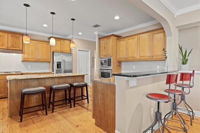 5373 Anthony Ln, Sarasota, FL 34233 - kitchen featuring stainless steel appliances, light wood-style flooring, a kitchen bar, recessed lighting, and tasteful backsplash