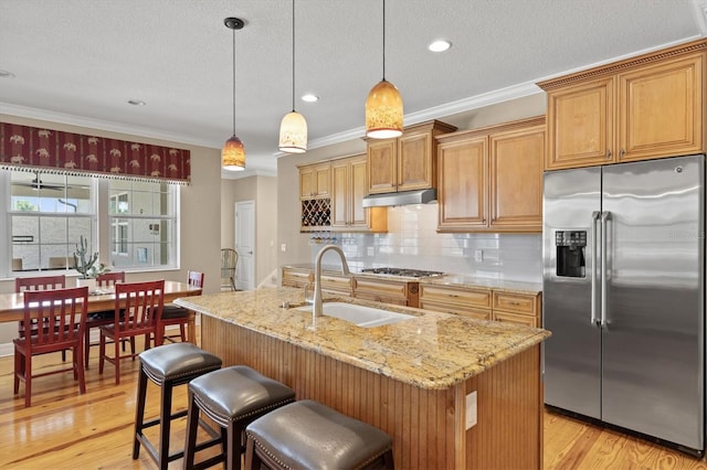 5373 Anthony Ln, Sarasota, FL 34233 - kitchen with appliances with stainless steel finishes, a sink, light stone countertops, backsplash, and light wood-style flooring