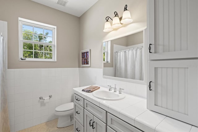 5373 Anthony Ln, Sarasota, FL 34233 - full bath featuring vanity, toilet, tile patterned flooring, tile walls, and wainscoting