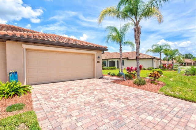 12230 Amica Loop, Venice, FL 34293 - mediterranean / spanish-style home featuring stucco siding, decorative driveway, an attached garage, a front lawn, and a tiled roof