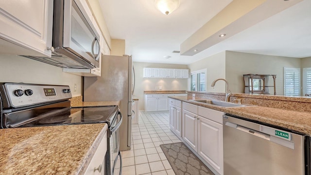 4308 Kingston Loop, Sarasota, FL 34238 - kitchen with appliances with stainless steel finishes, a sink, light tile patterned floors, white cabinetry, and light countertops