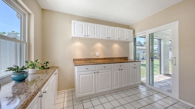 4308 Kingston Loop, Sarasota, FL 34238 - kitchen with white cabinetry, baseboards, light stone countertops, and light tile patterned floors