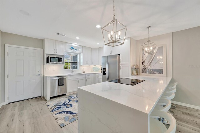 9822 Desoto Ct, Bradenton, FL 34210 - kitchen featuring stainless steel appliances, a chandelier, light wood-style floors, white cabinets, and recessed lighting