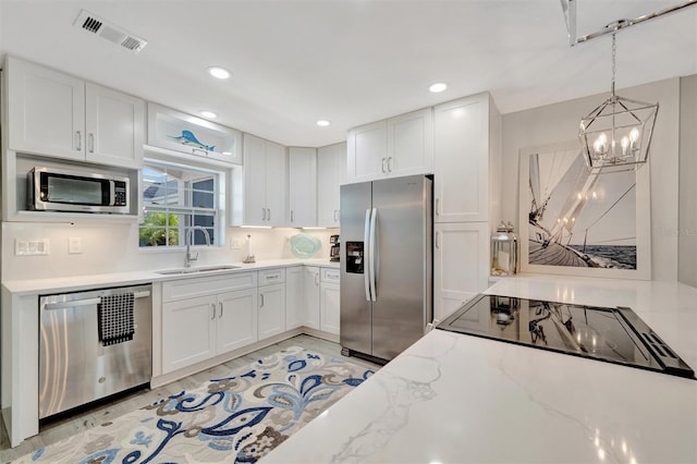 9822 Desoto Ct, Bradenton, FL 34210 - kitchen with appliances with stainless steel finishes, a sink, a chandelier, white cabinets, and recessed lighting