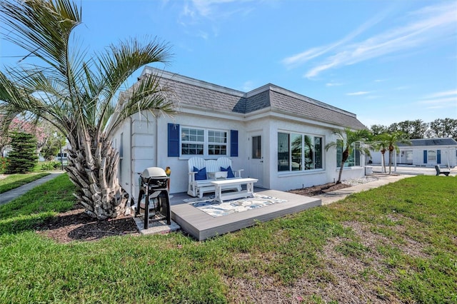9822 Desoto Ct, Bradenton, FL 34210 - back of house featuring mansard roof, a wooden deck, a lawn, a shingled roof, and stucco siding