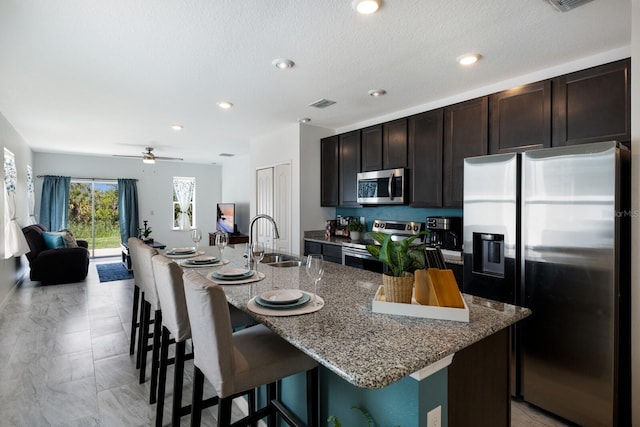 4739 Reisswood Loop, Palmetto, FL 34221 - kitchen featuring appliances with stainless steel finishes, a sink, a breakfast bar, stone countertops, and open floor plan