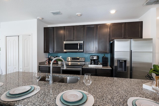 4739 Reisswood Loop, Palmetto, FL 34221 - kitchen with appliances with stainless steel finishes, a sink, dark brown cabinets, and dark stone counters