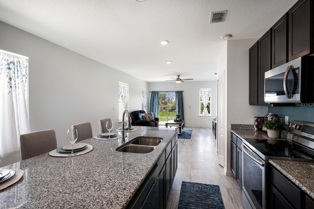 4739 Reisswood Loop, Palmetto, FL 34221 - kitchen featuring stainless steel appliances, a sink, dark stone counters, open floor plan, and a textured ceiling