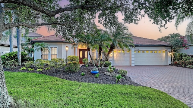 6914 Dominion Ln, Lakewood Ranch, FL 34202 - mediterranean / spanish-style house featuring an attached garage, decorative driveway, stucco siding, and a tiled roof