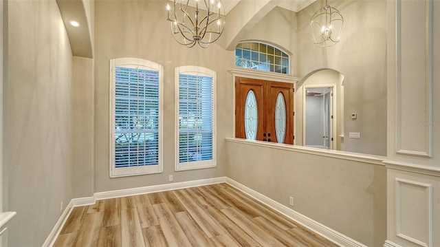 6914 Dominion Ln, Lakewood Ranch, FL 34202 - entrance foyer featuring a chandelier, baseboards, a high ceiling, wood finished floors, and arched walkways