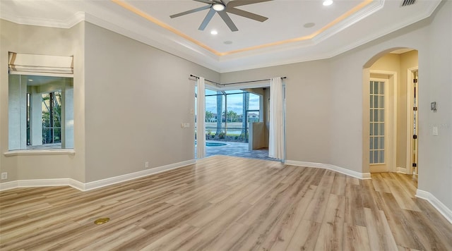 6914 Dominion Ln, Lakewood Ranch, FL 34202 - spare room with ceiling fan, crown molding, light wood-style flooring, arched walkways, and a raised ceiling