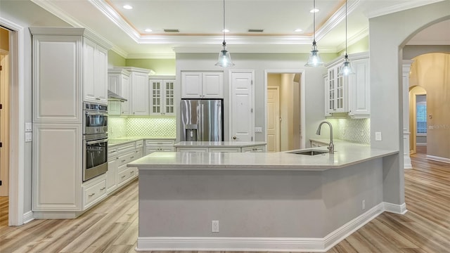 6914 Dominion Ln, Lakewood Ranch, FL 34202 - kitchen featuring a sink, appliances with stainless steel finishes, arched walkways, a peninsula, and light wood finished floors