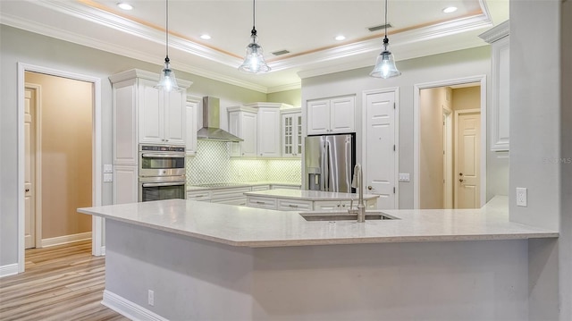 6914 Dominion Ln, Lakewood Ranch, FL 34202 - kitchen with stainless steel appliances, a sink, wall chimney range hood, a tray ceiling, and crown molding