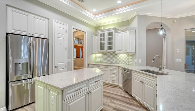 6914 Dominion Ln, Lakewood Ranch, FL 34202 - kitchen with stainless steel appliances, a sink, crown molding, arched walkways, and light stone counters