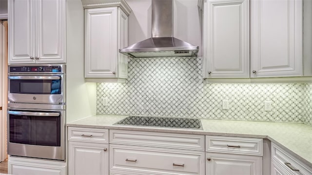 6914 Dominion Ln, Lakewood Ranch, FL 34202 - kitchen featuring wall chimney range hood, stainless steel double oven, black electric stovetop, light countertops, and decorative backsplash