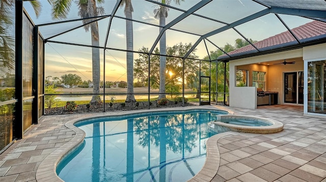 6914 Dominion Ln, Lakewood Ranch, FL 34202 - pool at dusk featuring a patio area, a pool with connected hot tub, ceiling fan, and glass enclosure