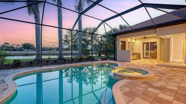 6914 Dominion Ln, Lakewood Ranch, FL 34202 - pool at dusk featuring a pool with connected hot tub, ceiling fan, a patio area, and a lanai