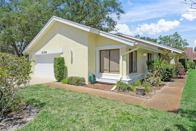 4109 Carriage Dr Unit 23, Sarasota, FL 34241 - view of property exterior featuring a garage, stucco siding, a lawn, and concrete driveway