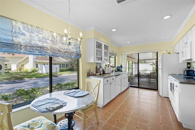 4109 Carriage Dr Unit 23, Sarasota, FL 34241 - kitchen with crown molding, white appliances, white cabinets, glass insert cabinets, and dark countertops