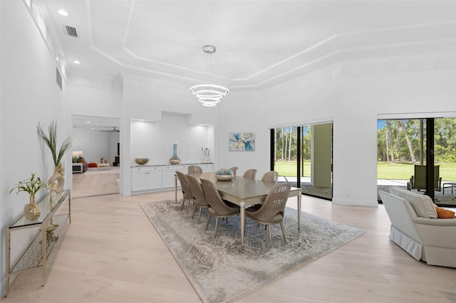 7051 Turtle Ln, Sarasota, FL 34241 - dining space with a tray ceiling, a high ceiling, a chandelier, light wood-type flooring, and recessed lighting