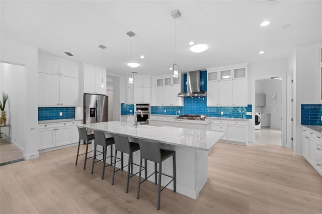 7051 Turtle Ln, Sarasota, FL 34241 - kitchen featuring a spacious island, decorative backsplash, a breakfast bar area, wall chimney exhaust hood, and light wood-style flooring