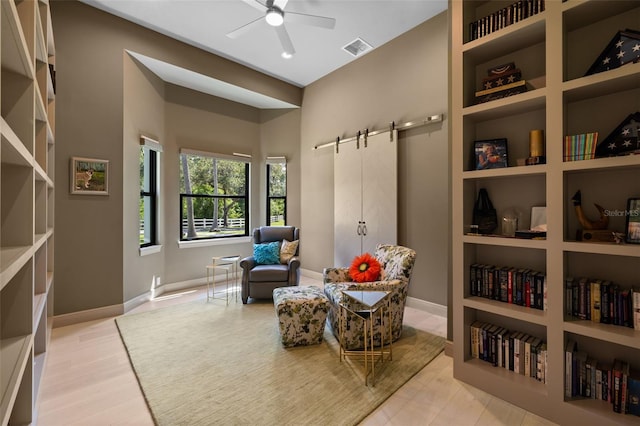 7051 Turtle Ln, Sarasota, FL 34241 - sitting room with a barn door, ceiling fan, built in features, and light wood-type flooring