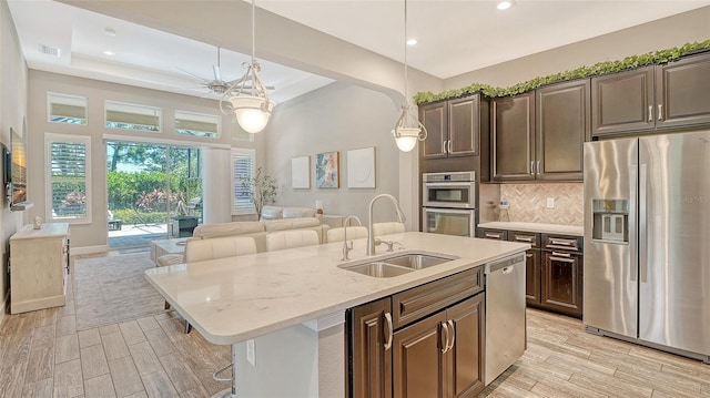 11603 Bluebird Pl, Lakewood Ranch, FL 34211 - kitchen featuring appliances with stainless steel finishes, a sink, open floor plan, light wood-style floors, and recessed lighting