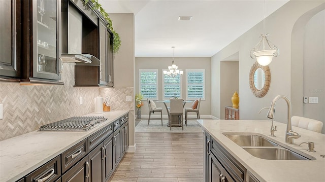 11603 Bluebird Pl, Lakewood Ranch, FL 34211 - kitchen featuring a sink, stainless steel gas stovetop, light wood-style floors, wall chimney exhaust hood, and decorative backsplash