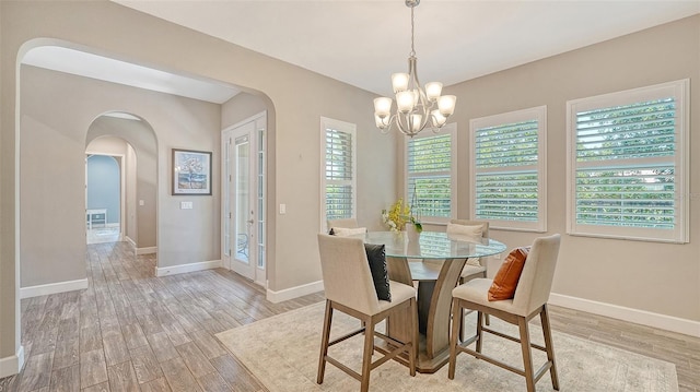 11603 Bluebird Pl, Lakewood Ranch, FL 34211 - dining area with arched walkways, light wood-style floors, healthy amount of natural light, and a chandelier