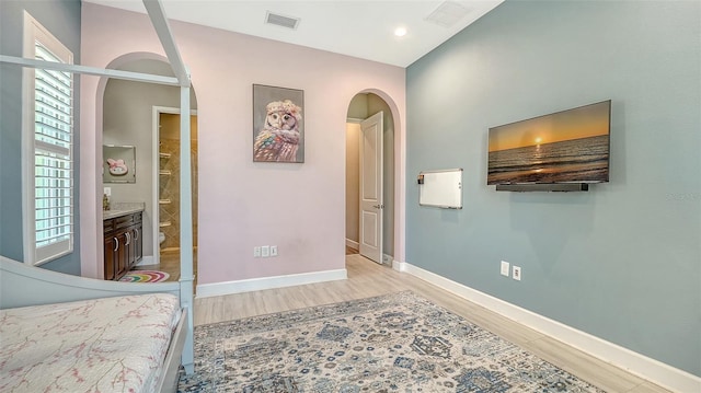 11603 Bluebird Pl, Lakewood Ranch, FL 34211 - bedroom with arched walkways, light wood-style flooring, baseboards, ensuite bath, and recessed lighting