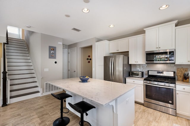 11411 Spring Gate Trl, Bradenton, FL 34211 - kitchen featuring stainless steel appliances, a center island, recessed lighting, white cabinets, and backsplash