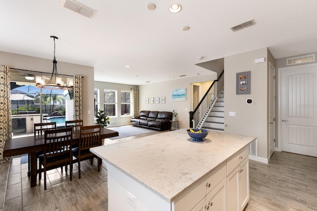 11411 Spring Gate Trl, Bradenton, FL 34211 - kitchen with light wood-style floors, white cabinetry, a kitchen island, hanging light fixtures, and recessed lighting