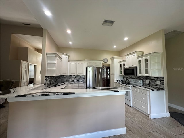 3192 Oaks Bnd, Bowling Green, FL 33834 - kitchen with stainless steel appliances, a peninsula, tasteful backsplash, glass insert cabinets, and recessed lighting
