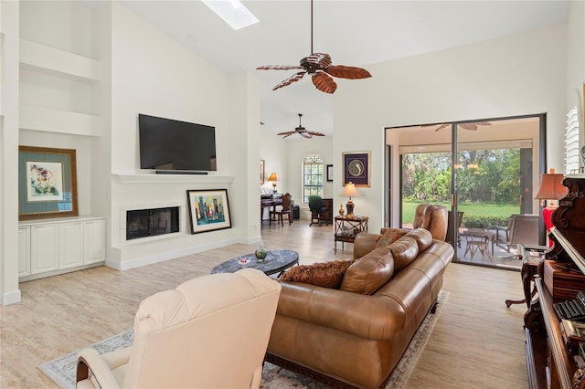 7331 Villa D Este Dr, Sarasota, FL 34238 - living room with ceiling fan, high vaulted ceiling, wood finished floors, a skylight, and a glass covered fireplace
