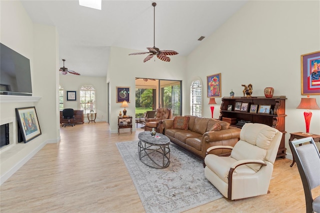 7331 Villa D Este Dr, Sarasota, FL 34238 - living area featuring ceiling fan, light wood finished floors, high vaulted ceiling, a fireplace with raised hearth, and baseboards