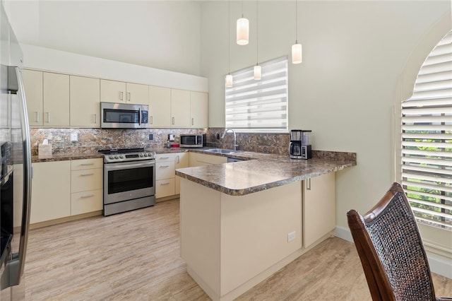 7331 Villa D Este Dr, Sarasota, FL 34238 - kitchen with appliances with stainless steel finishes, a peninsula, light wood-style floors, dark countertops, and a high ceiling