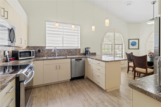 7331 Villa D Este Dr, Sarasota, FL 34238 - kitchen with stainless steel appliances, a sink, a peninsula, light wood-style floors, and pendant lighting