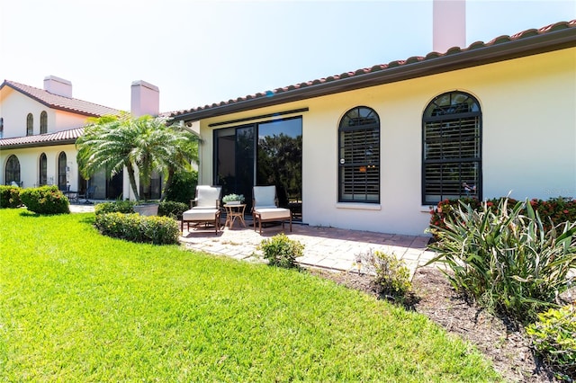 7331 Villa D Este Dr, Sarasota, FL 34238 - back of property with a yard, a patio, a tiled roof, a chimney, and stucco siding