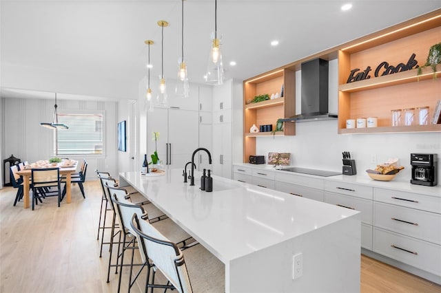 103 4th St N Unit A, Bradenton Beach, FL 34217 - kitchen featuring wall chimney range hood, open shelves, light countertops, black electric cooktop, and light wood-style floors